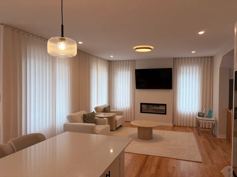 Soft white curtains framing a warm living room with a fireplace and neutral furnishings