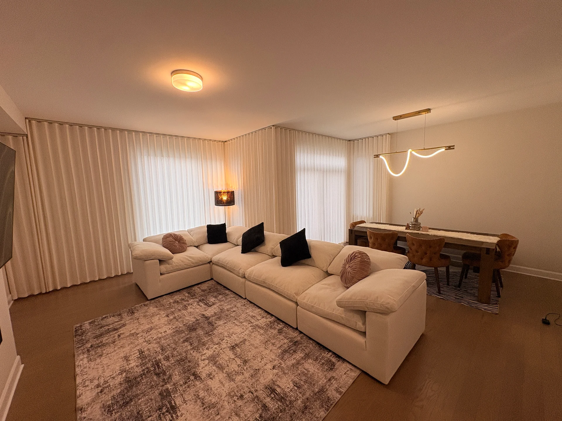 Soft white drapery framing a warm, inviting living and dining room