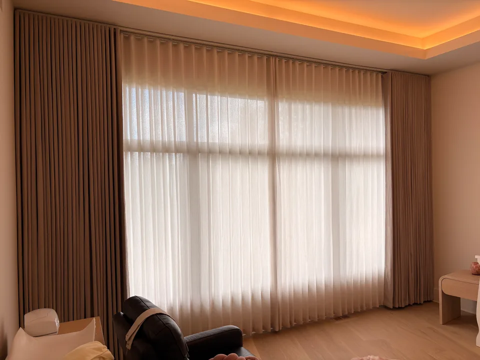Layered bedroom curtains beneath warm cove lighting