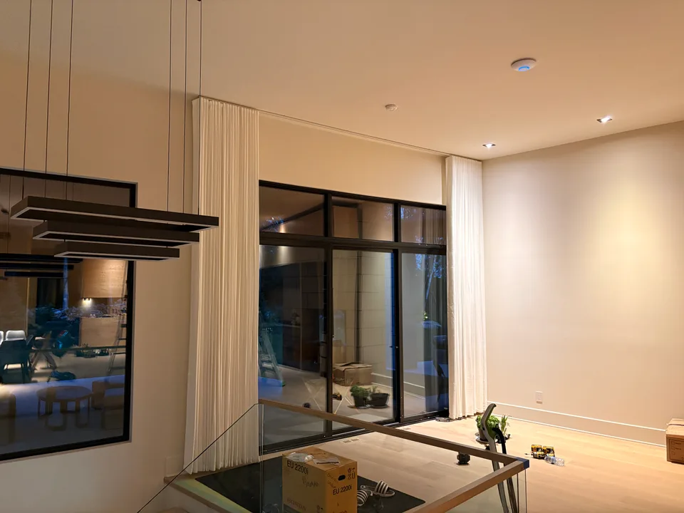 White curtains being installed around tall black-framed windows